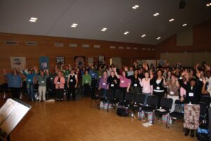 Group of people raising hands in a conference room.