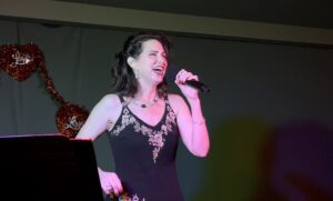 A woman singing passionately on stage with a microphone.