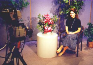 Woman sitting on a stool with a bouquet of flowers in a studio setting.