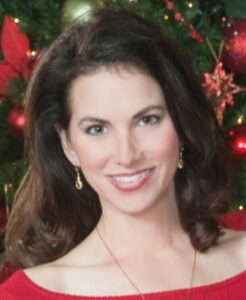 A woman smiling in front of a festive red background.
